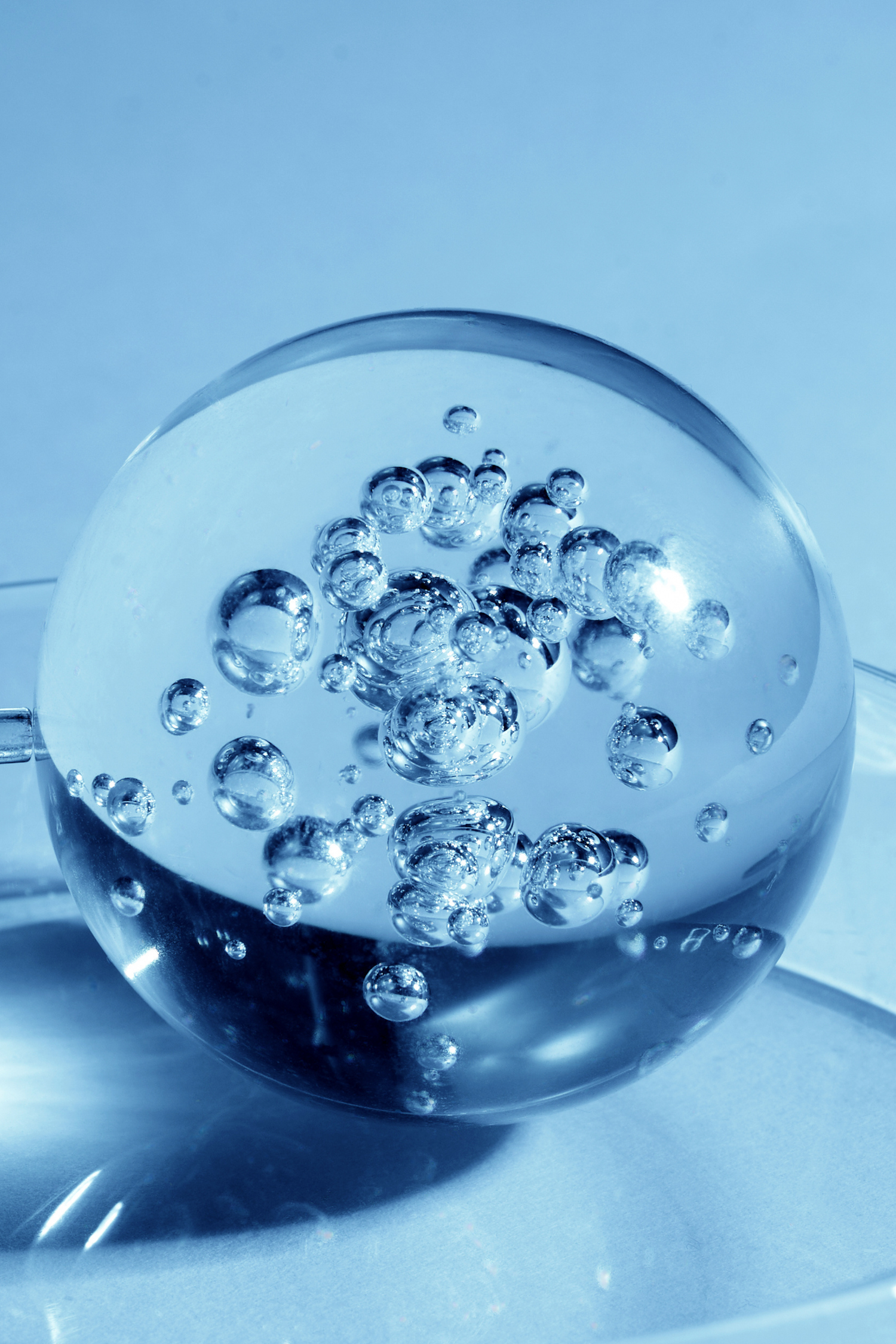 Szklana kula z pęcherzykami powietrza, symbolizująca innowacyjną formułę i stworzenie flagowego produktu KV-1: odmładzającej kuracji do włosów Anti-Aging Hair Lifting.